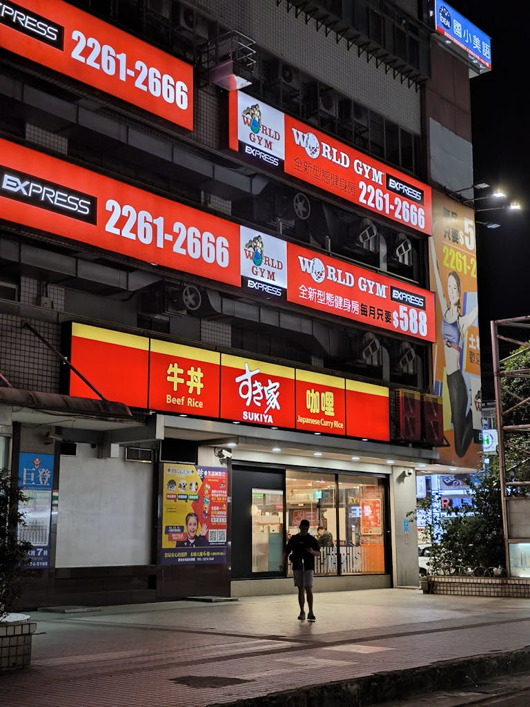 Asian city street with bright advertising signs illuminating the night, showcasing vibrant urban life.