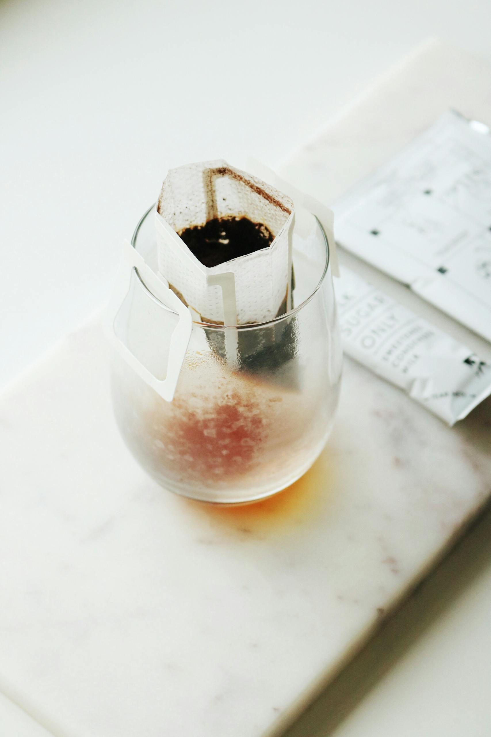 Close-up of a glass cup with a pour-over coffee filter, creating a classic caffeine experience.