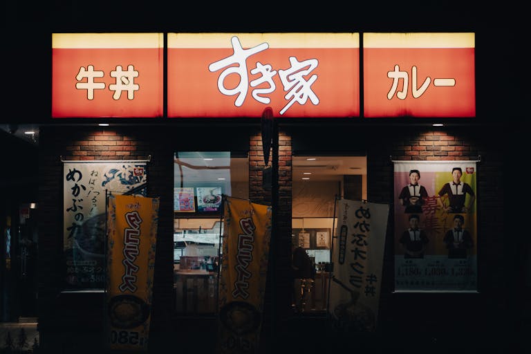 Night view of a Japanese restaurant in Toyohashi, Japan with illuminated signs.