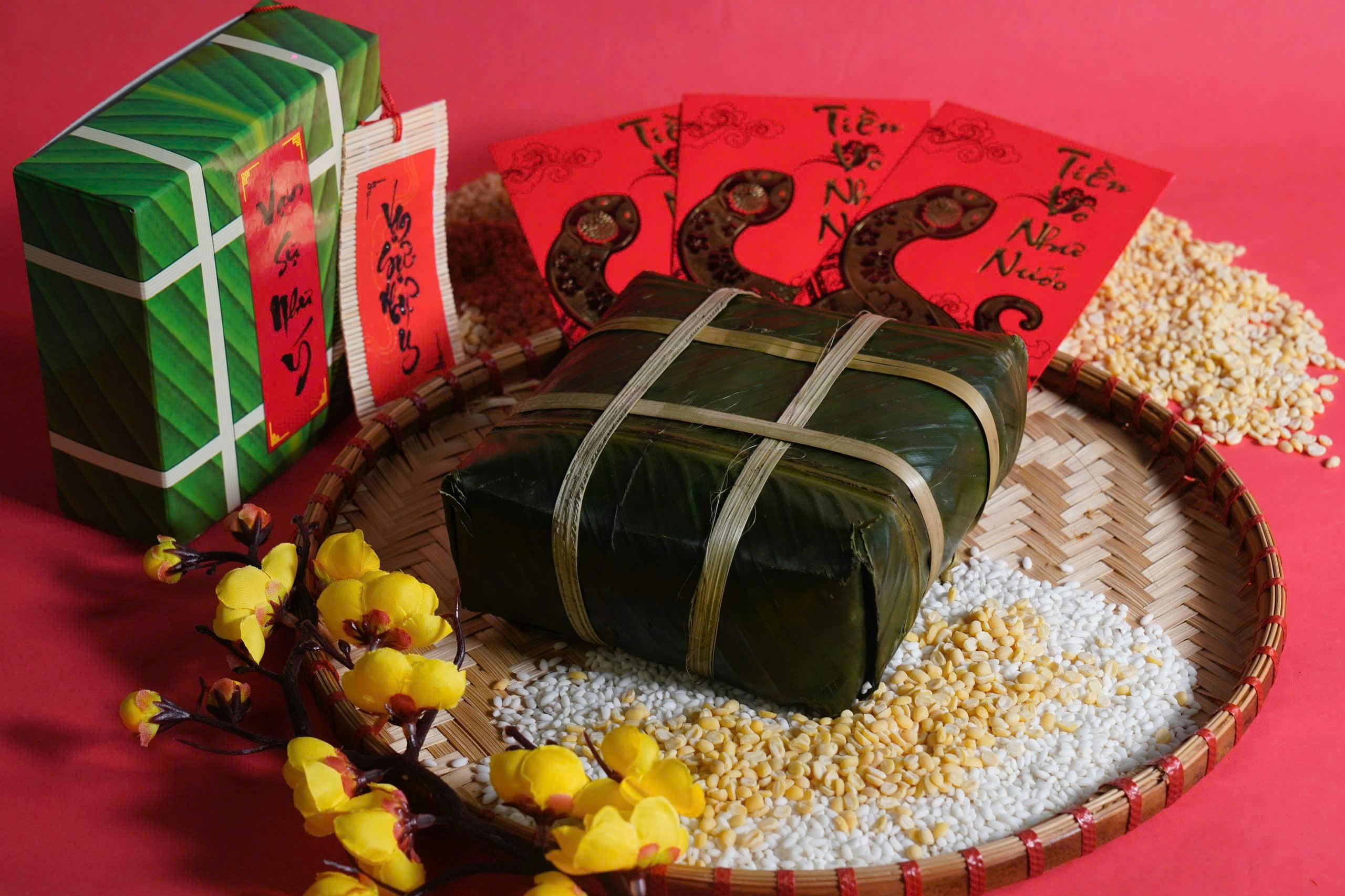 Vietnamese Tet gift set with banh chung, red envelopes, and flowers on a bamboo tray.