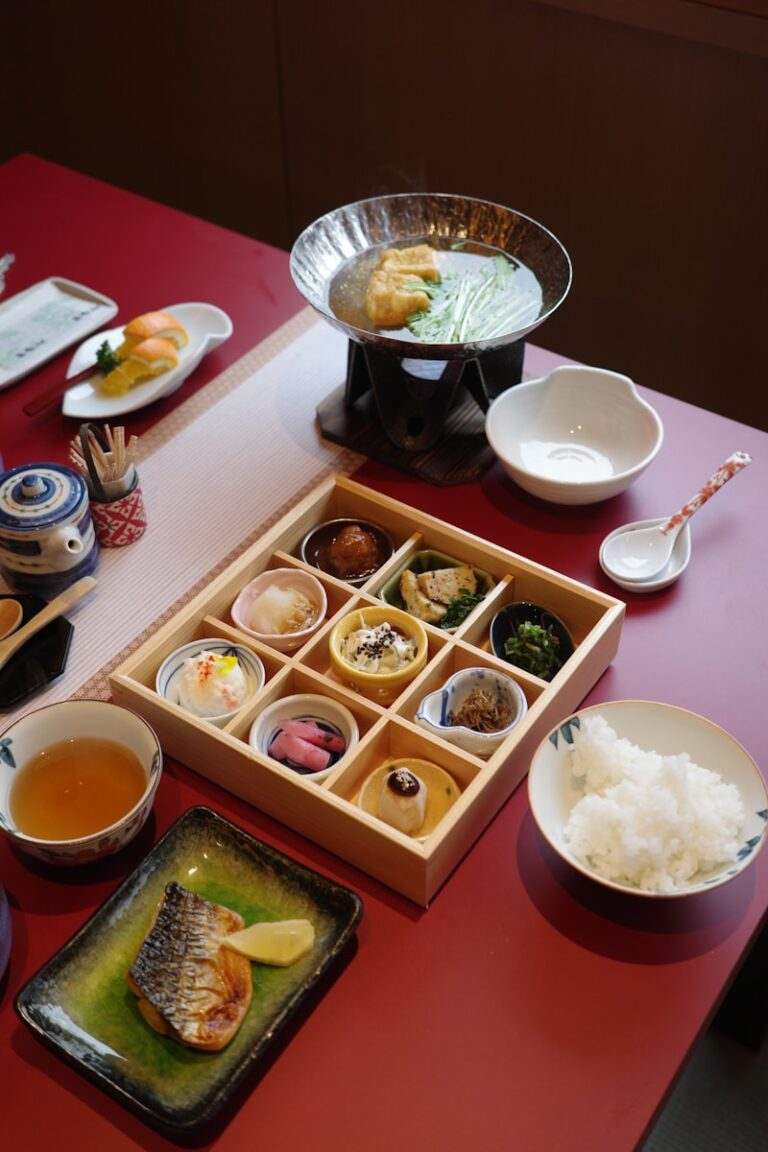 A red table topped with plates of food and bowls of soup