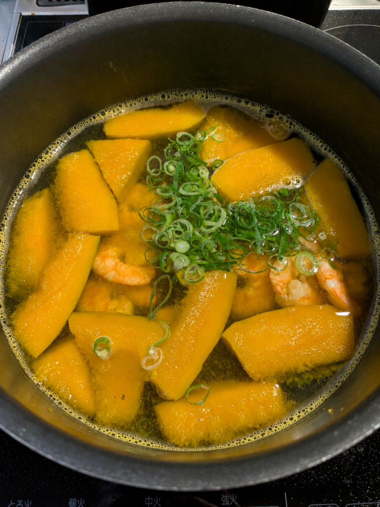 Bí đỏ kabocha và tôm đang nấu trong nồi với hành lá